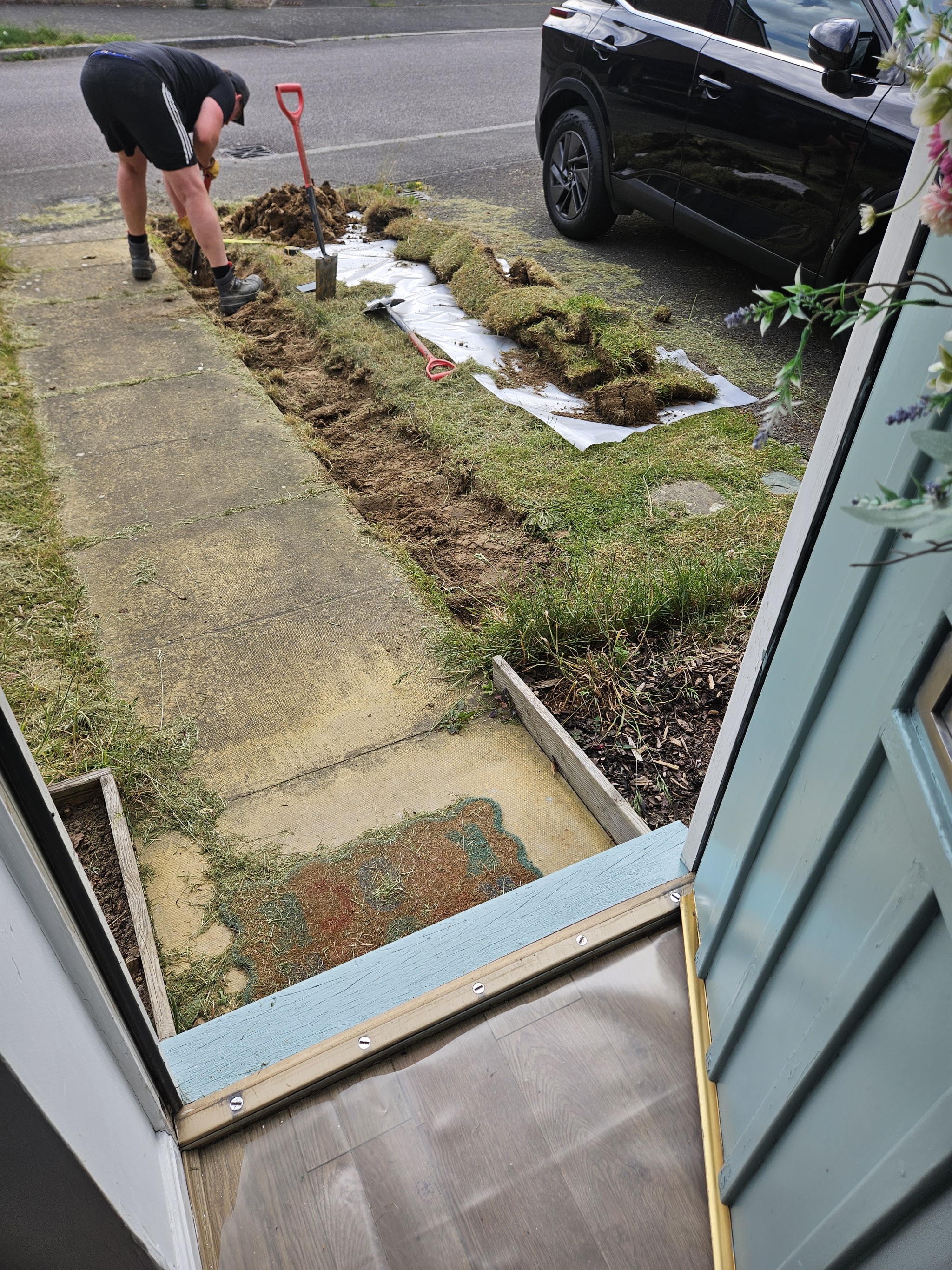 A trench across a front lawn with the turf lifted onto sheeting