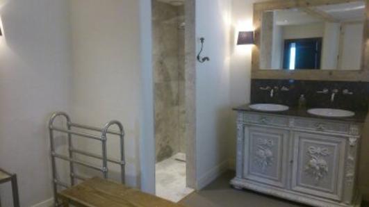 A bathroom with a white vanity unit, twin basins and a heated towel rail