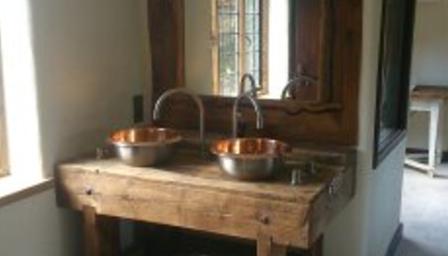 Twin copper basins on a rustic wooden bench under a leaded window