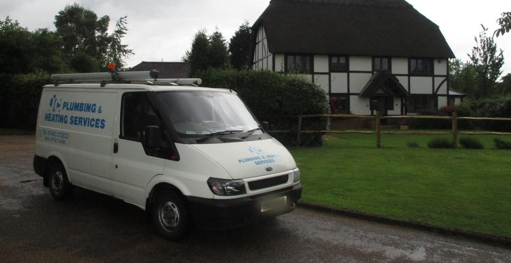 The JC Plumbing & Heating Services van outside a thatched timber-framed house