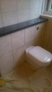 A newly fitted wall-hung toilet with dust sheets still down