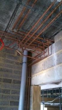 Copper pipe runs at ceiling level in a block-built extension